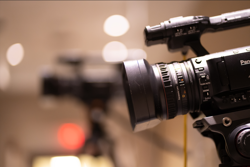 Professional video camera with blurred studio lights behind